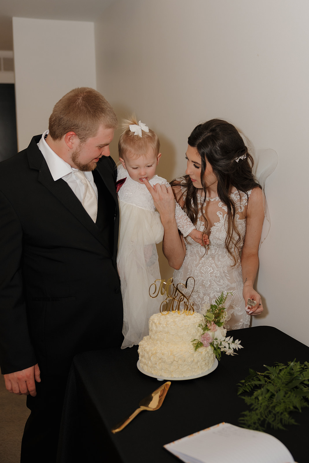 Bride and Groom cut their wedding cake with their daughter, the flower girl on dad's hip at the eloise in Mount horeb wisconsin