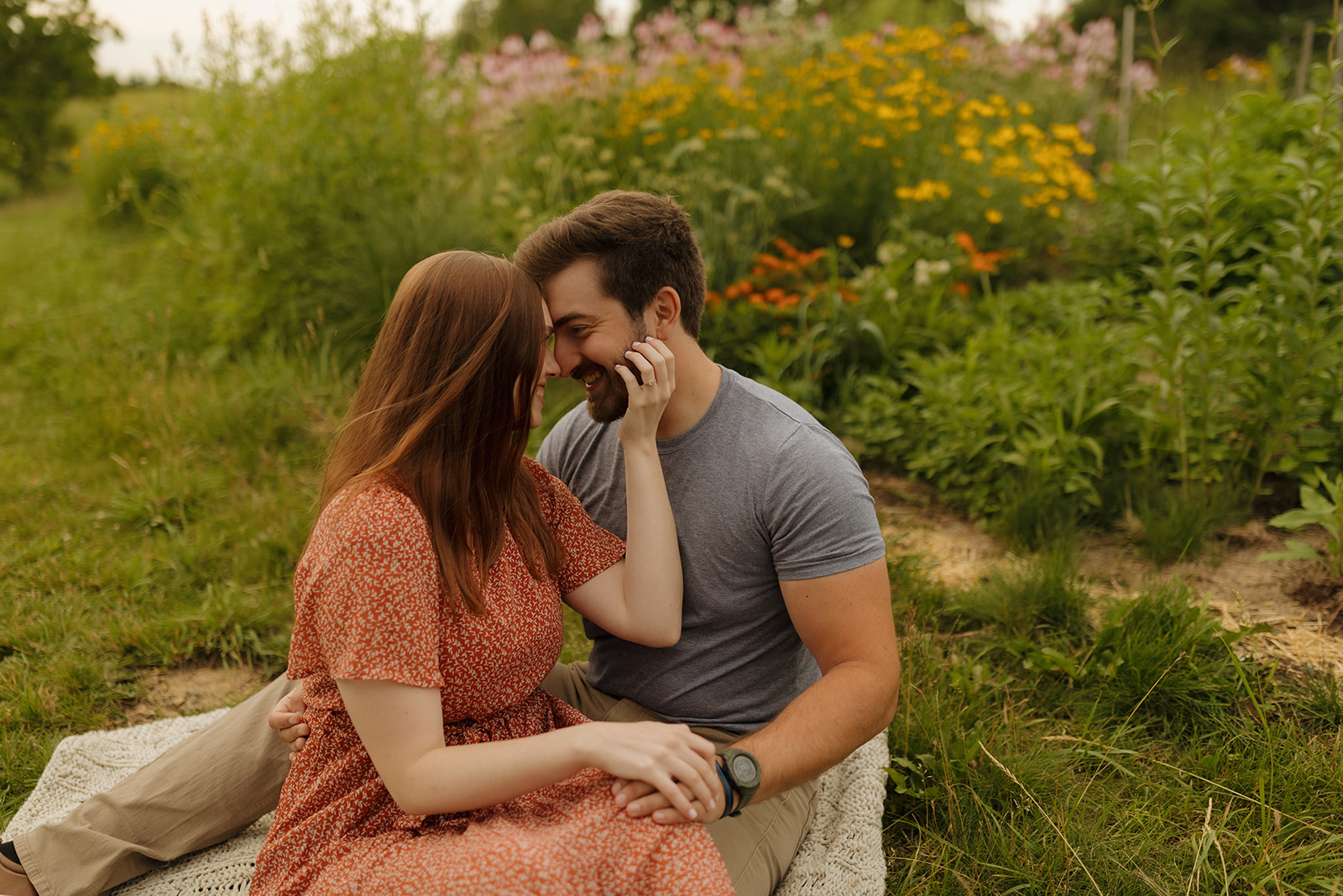 Engaged couple sitting in wildflower field in Mount Horeb wisconsin