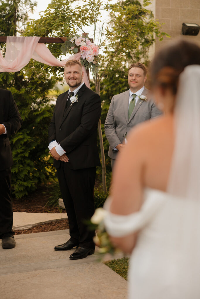 groom sees his bride for the first time walking down the aisle at their wedding