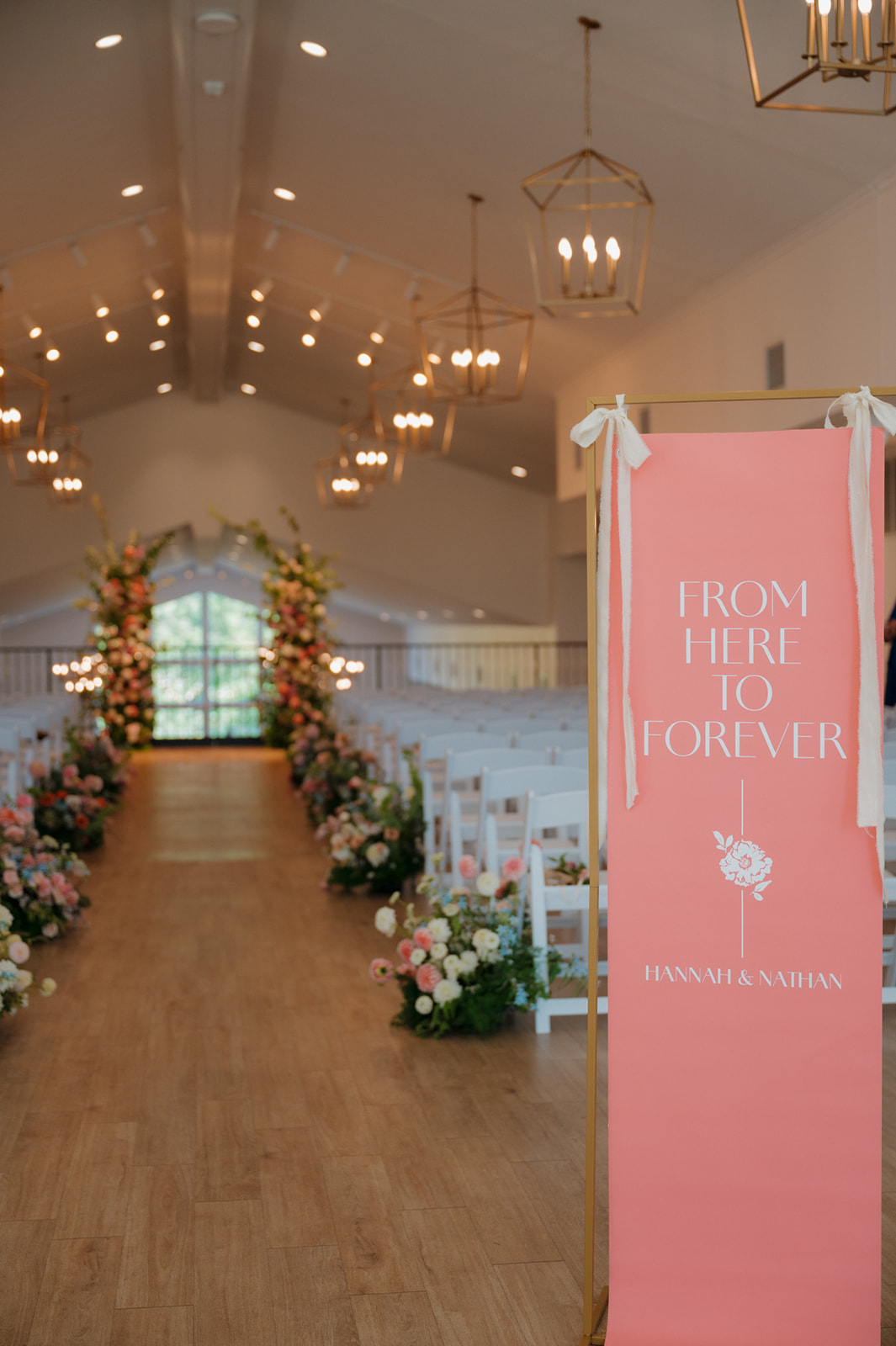 Wedding ceremony aisle with coral welcome sign and lush florals at The Eloise, a favorite wedding venue in Madison, WI