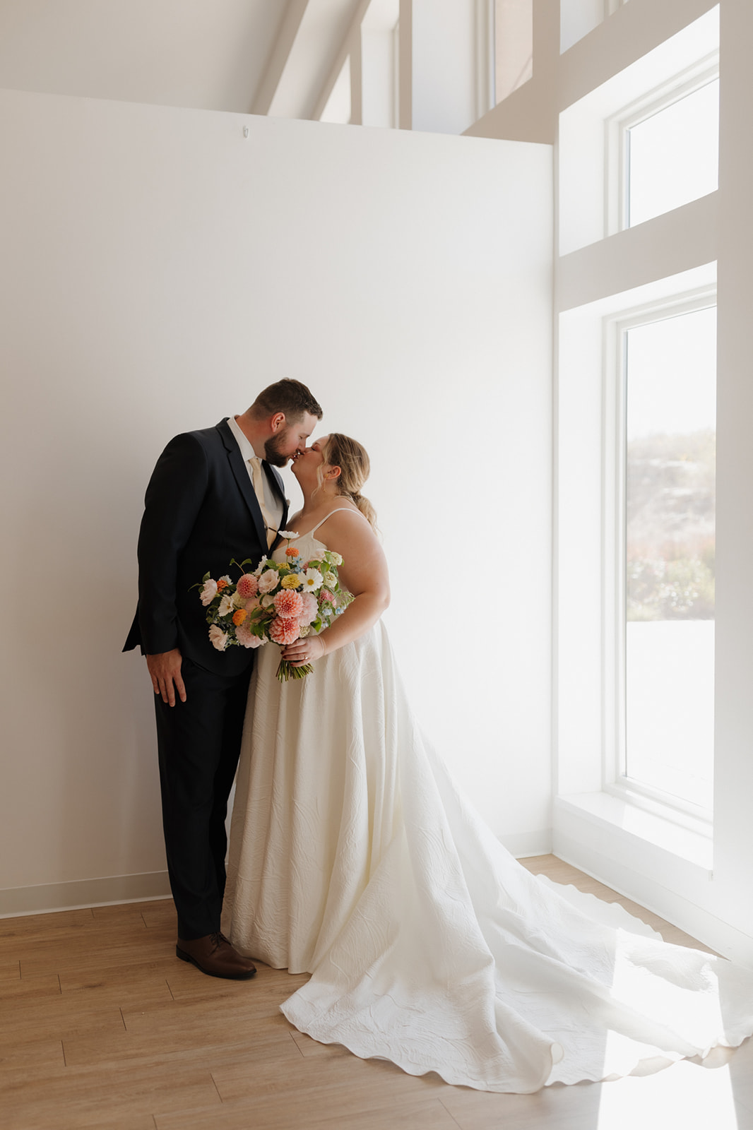Bride and groom kiss in front of a sunlit window at The Eloise wedding venue in Madison, Wisconsin