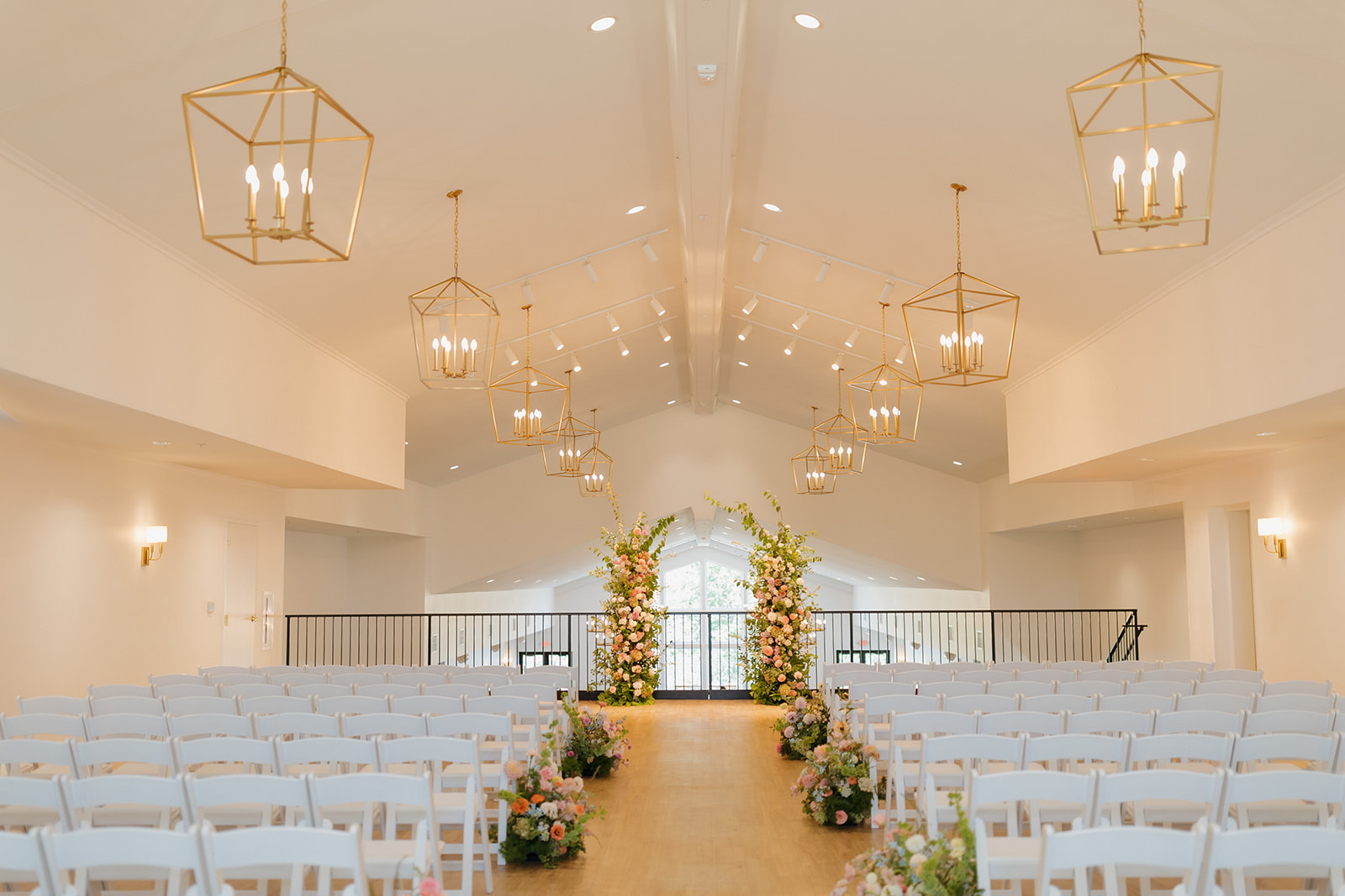 Indoor ceremony space at The Eloise, a modern wedding venue near Madison with floral aisle decor and gold chandeliers