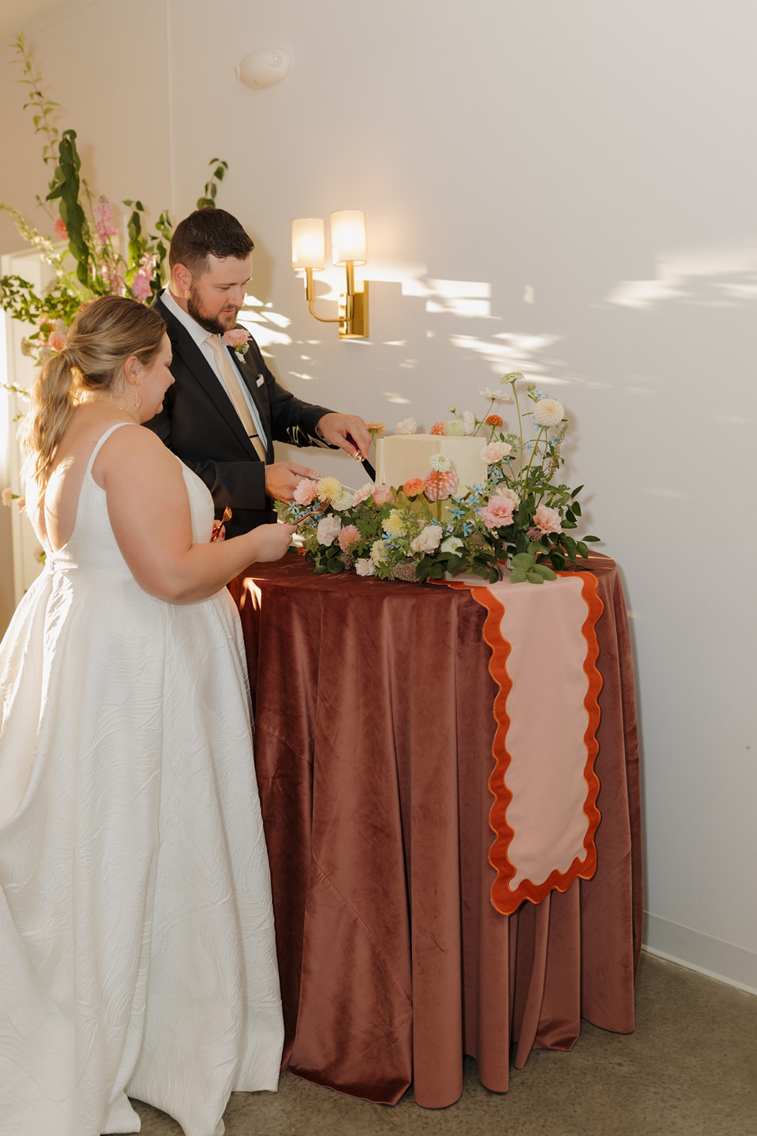 Couple cutting their wedding cake decorated with florals during their celebration at The Eloise in Madison