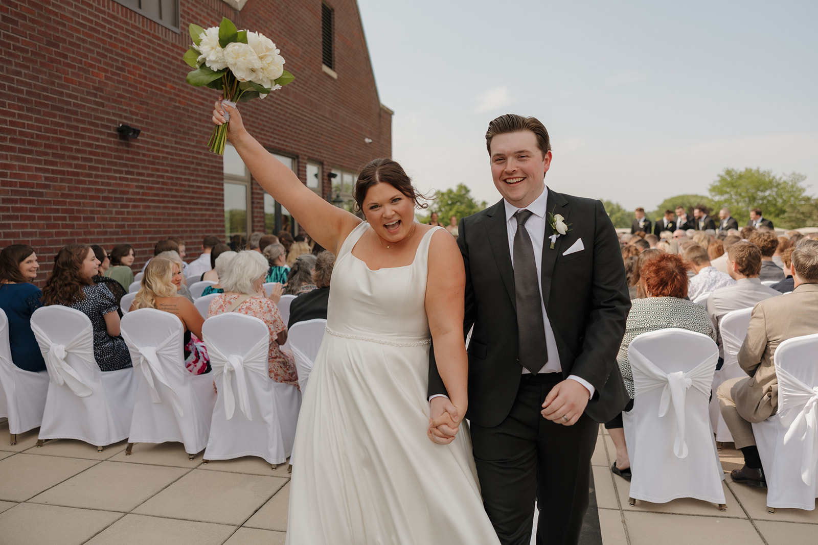 Just married couple celebrating down the aisle after their outdoor wedding ceremony at a venue near Madison, Wisconsin