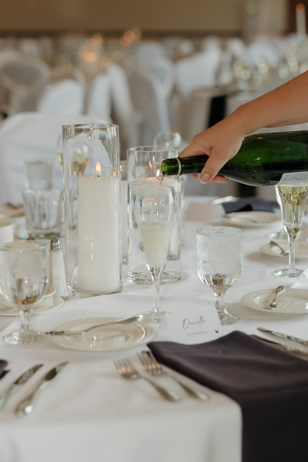 Champagne being poured at an elegant wedding reception table with candles and name cards in Madison, Wisconsin