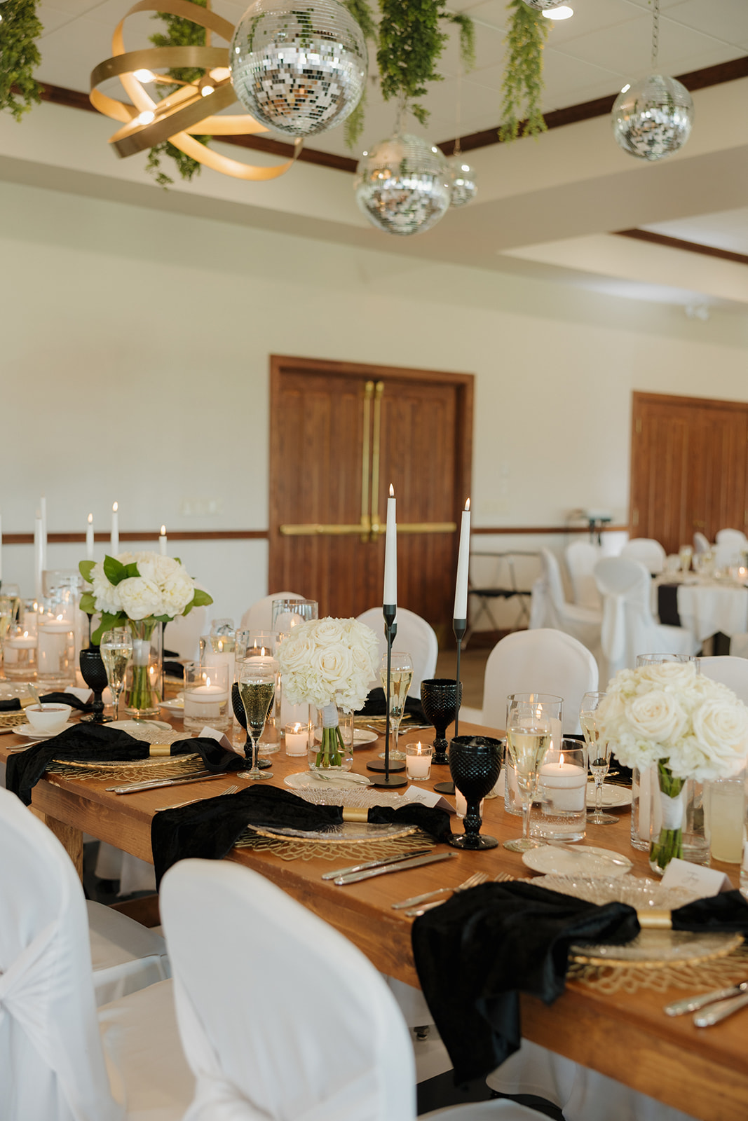Modern black and white wedding reception tablescape with florals, candles, and disco balls at a luxury venue near Madison