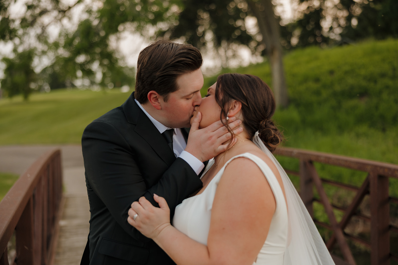 Bride and groom kissing on a bridge at Bishops Bay Country Club wedding venue near Madison, Wisconsin