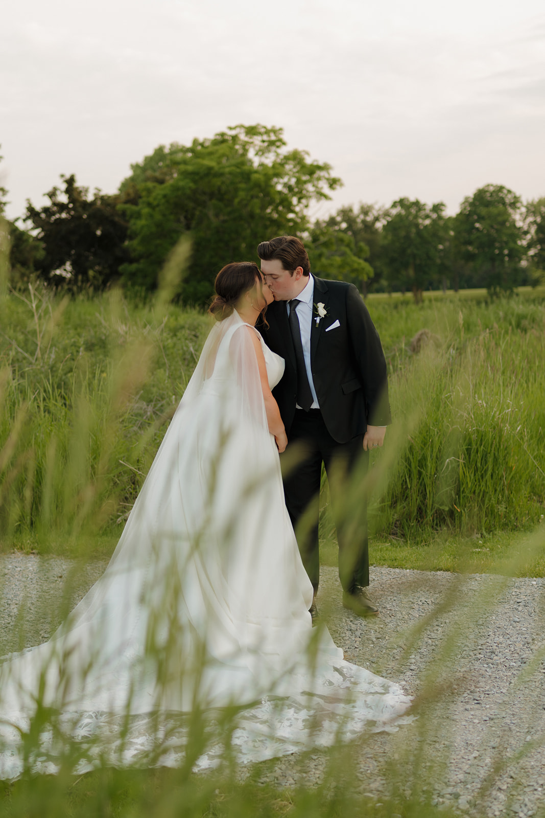 Couple kissing in a grassy field at sunset near a luxury wedding venue in Madison, WI
