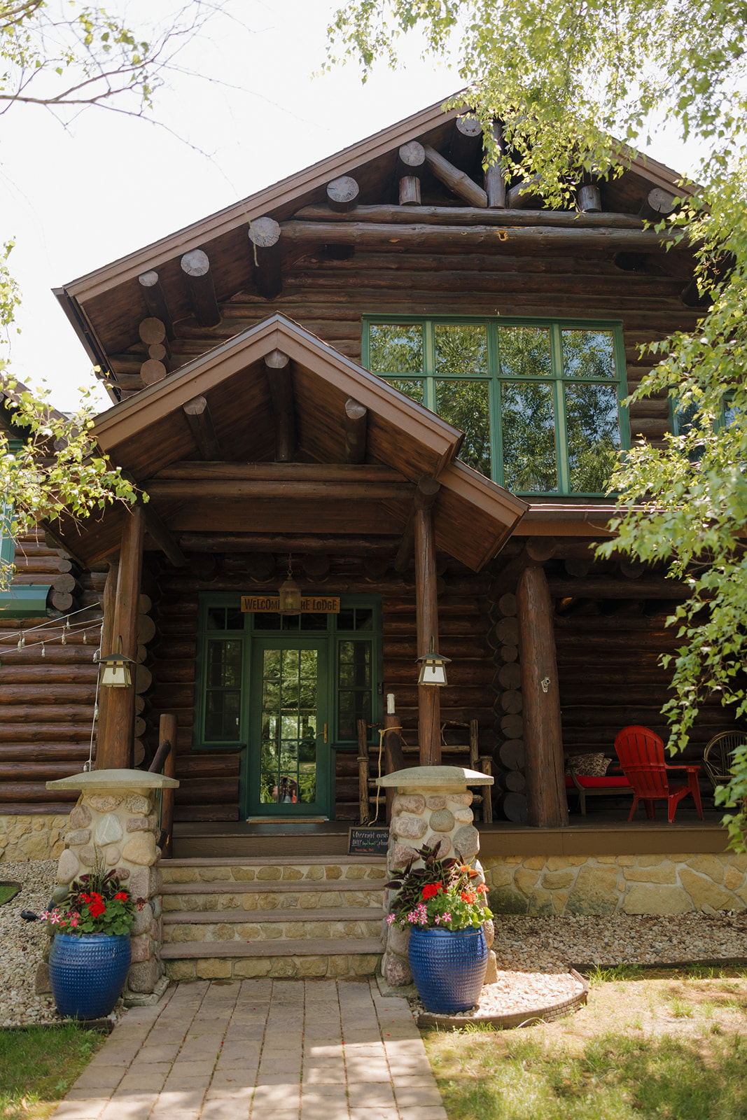 Front entrance of a rustic lodge surrounded by greenery, perfect for hosting an outdoor wedding in Wisconsin.

