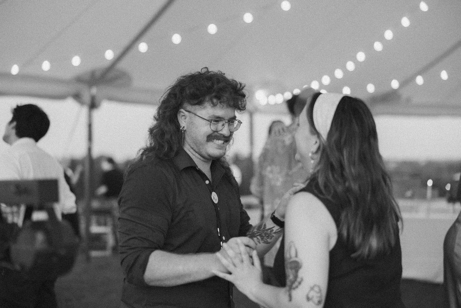 Guests laughing and dancing under twinkle lights during an outdoor wedding reception in Wisconsin.

