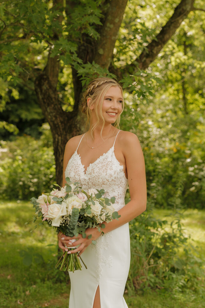 Bride looking over her shoulder while holding her elegant pink and white floral bouquet