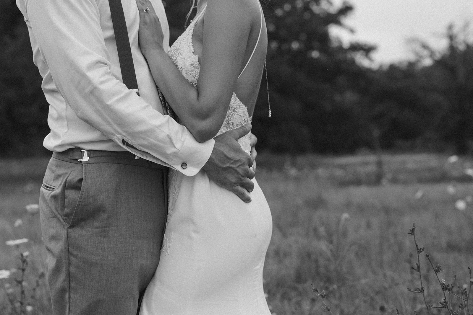 Close up of groom holding bride with his hands around her waist during outdoor bridal portraits