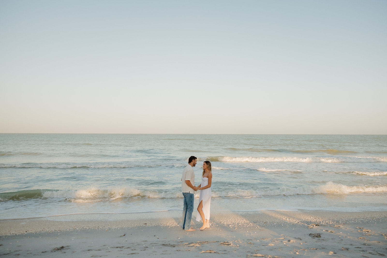 Couple holding hands at the shoreline, soft waves rolling in behind them during a florida elopement