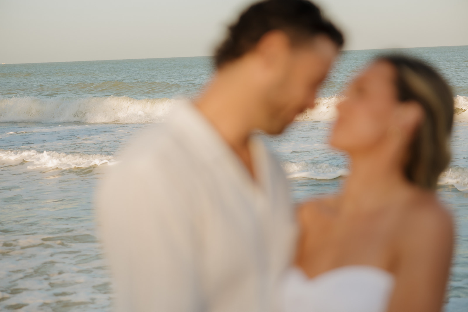 Couple blurred with ocean crashing behind them as main focus