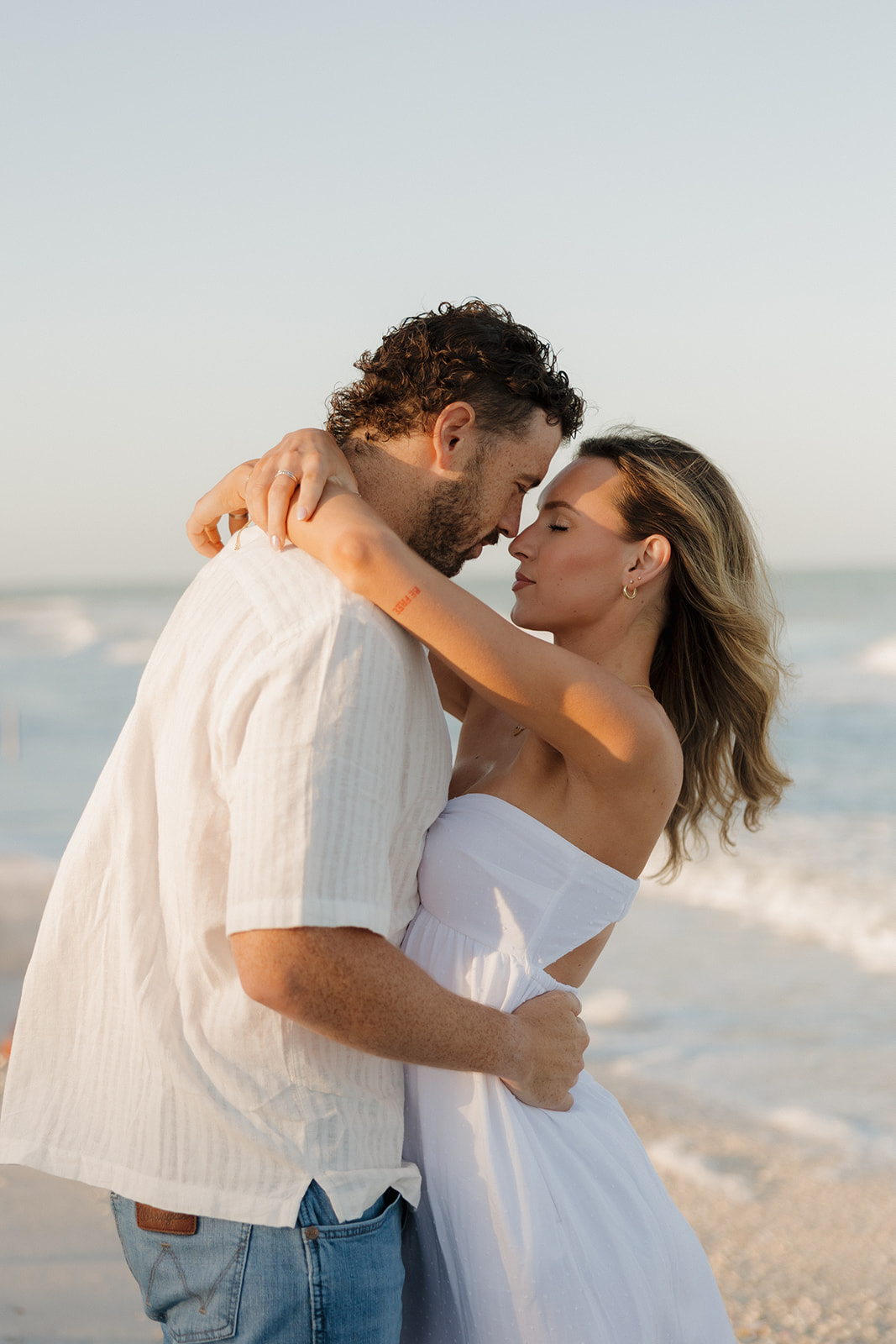 Couple embracing and pressing noses together while looking in each other's eyes on beach in Florida