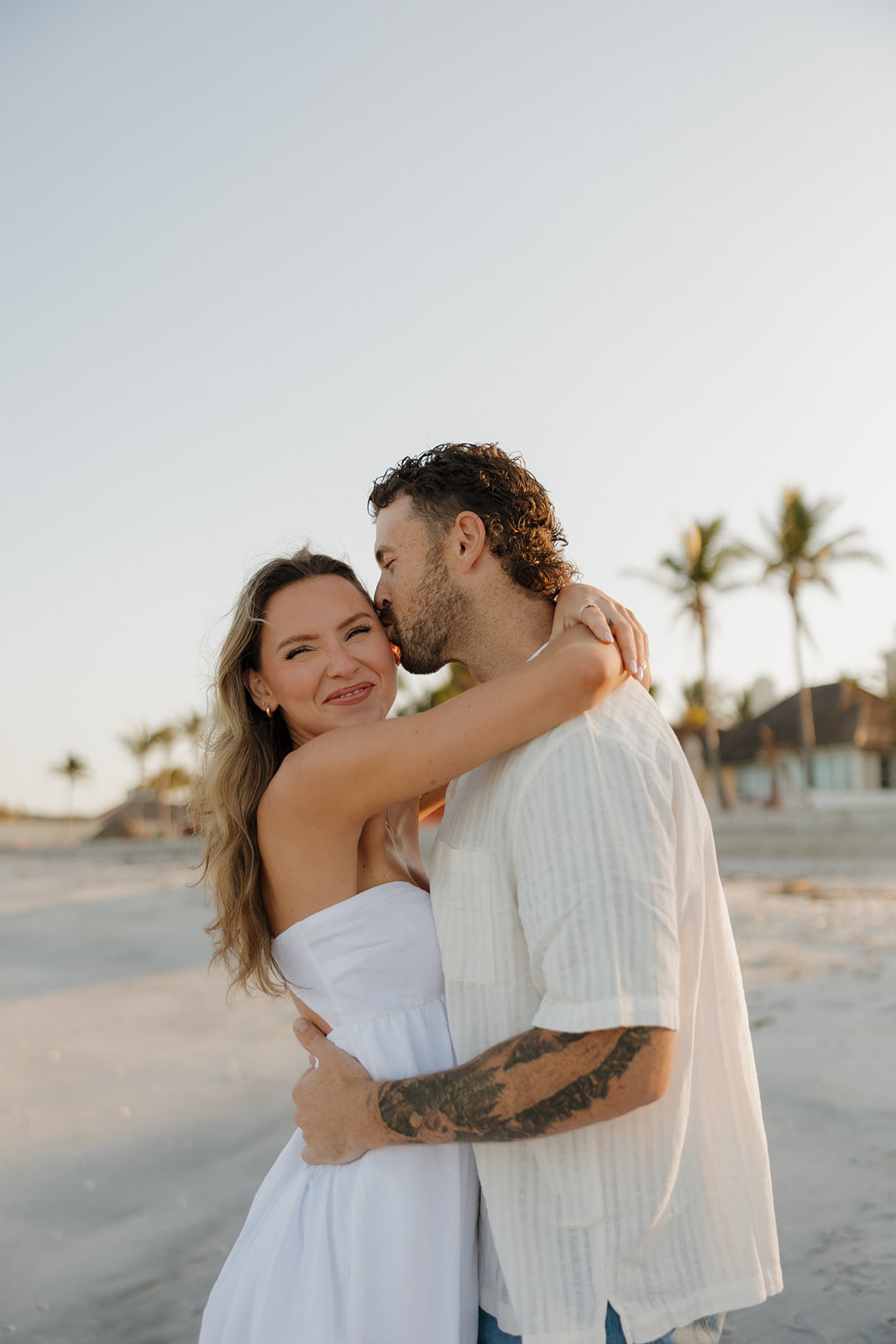 Woman smiling as her partner kisses her cheek during a romantic florida elopement on the beach
