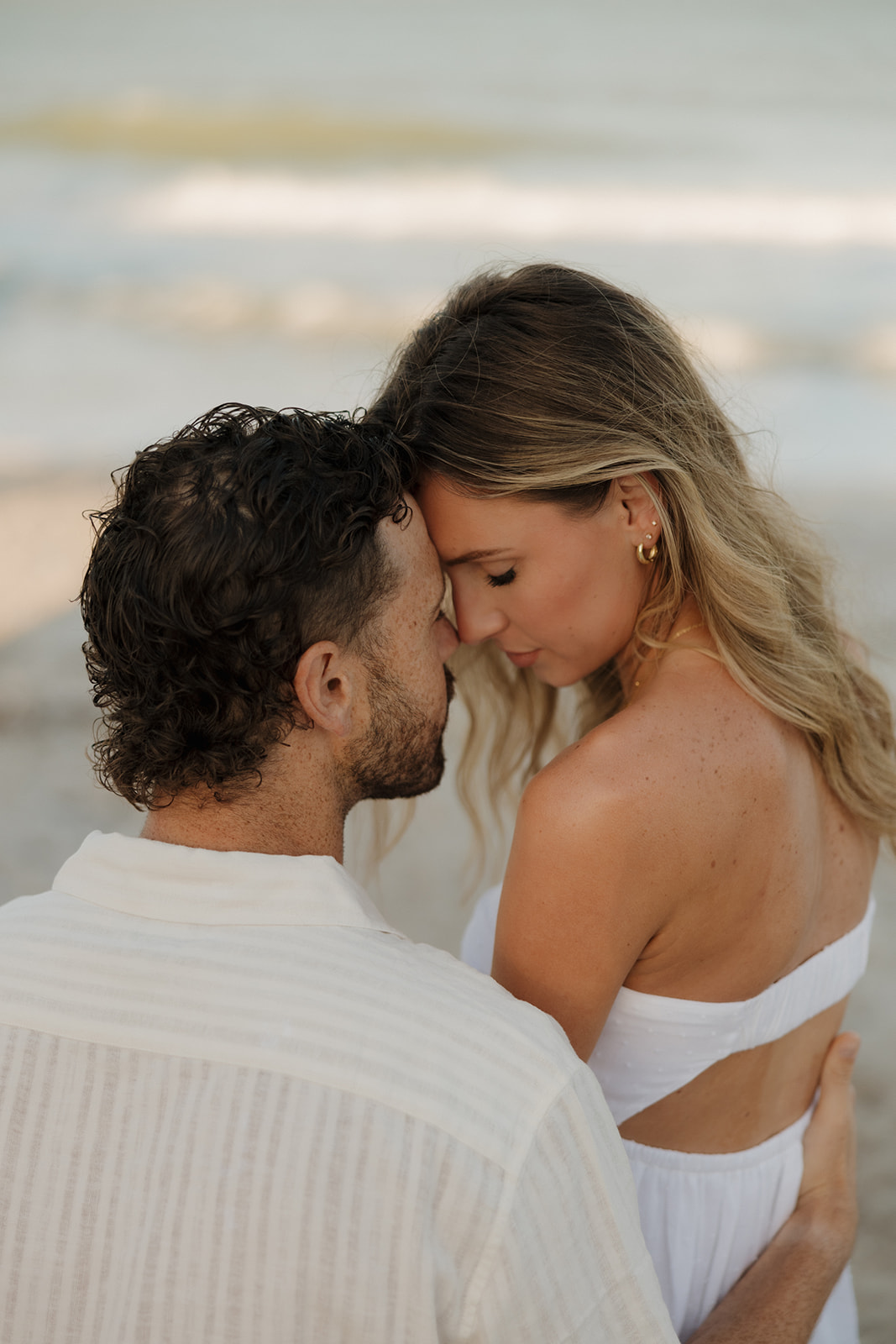 Woman sitting with man and touching foreheads after private Florida elopement on the beach