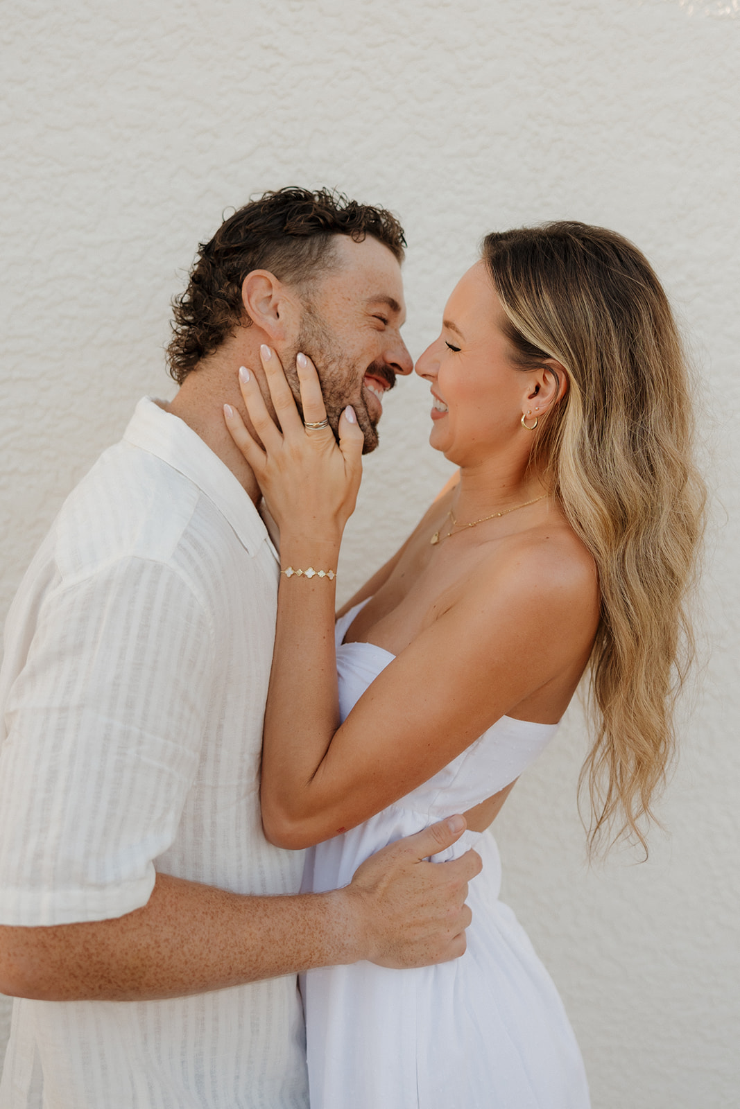Couple laughing and leaning into each other with playful energy during their florida elopement by a white textured wall