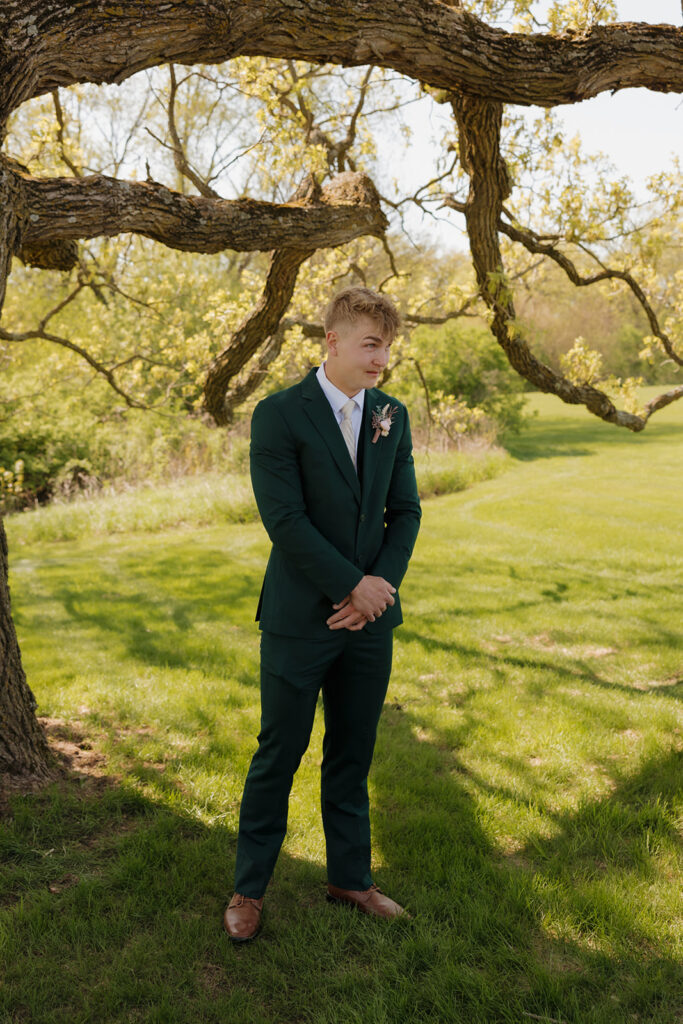 Groom stands alone under a large oak tree, waiting for his bride with anticipation and emotion – a simple yet powerful image that reflects the heart of intimate wedding ideas.