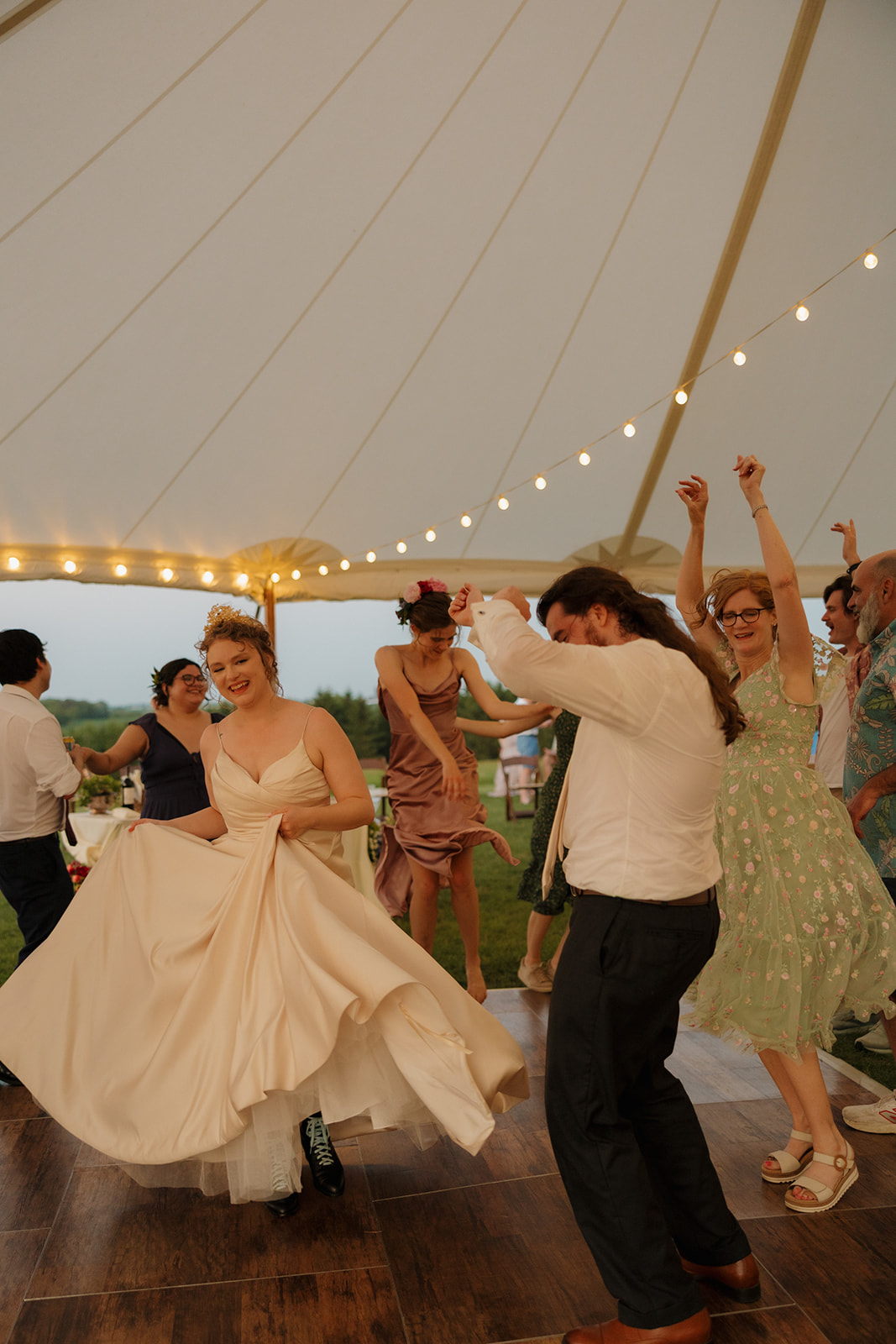 Guests and the couple hit the dance floor under a canopy of string lights, fully leaning into the celebration energy.

