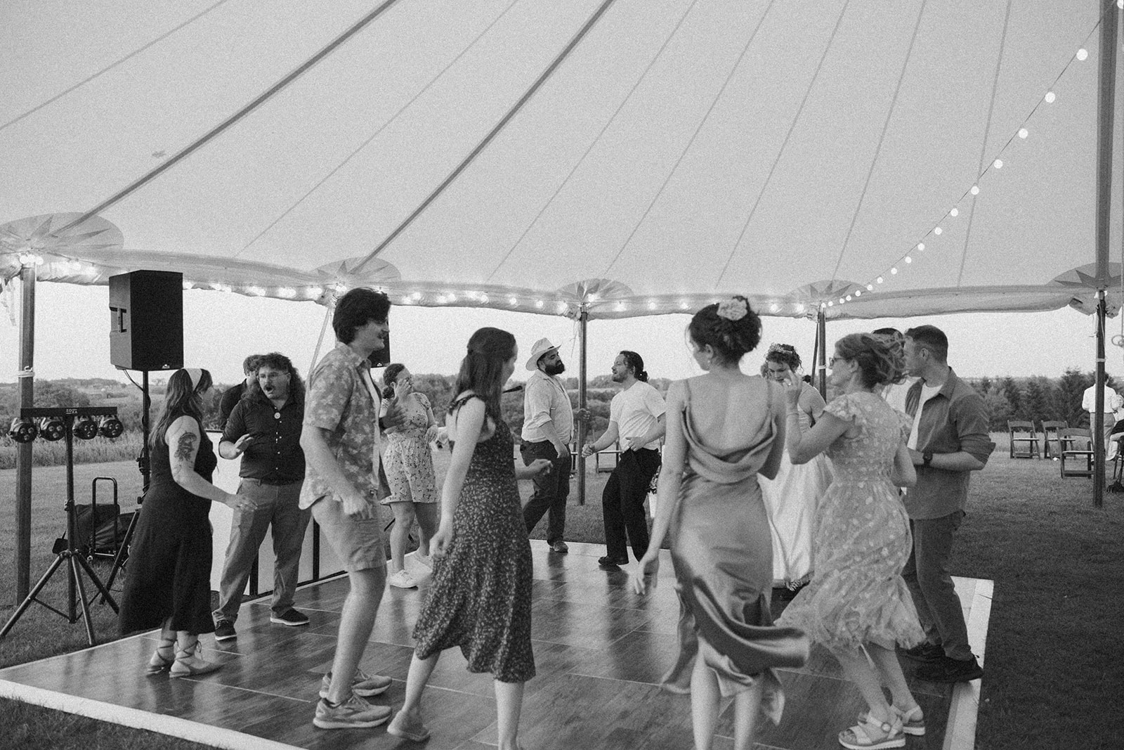 Black and white photo of friends and family dancing together under the tent, radiating pure wedding night joy.

