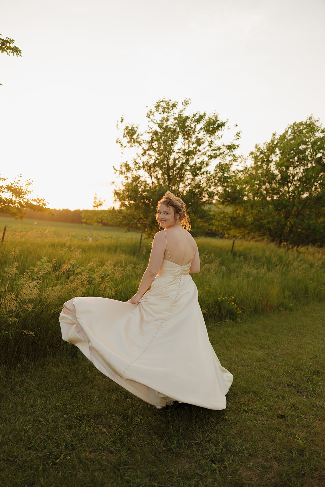 Golden hour glow surrounds the bride as she twirls joyfully in her dress during sunset at an outdoor wedding in Wisconsin.

