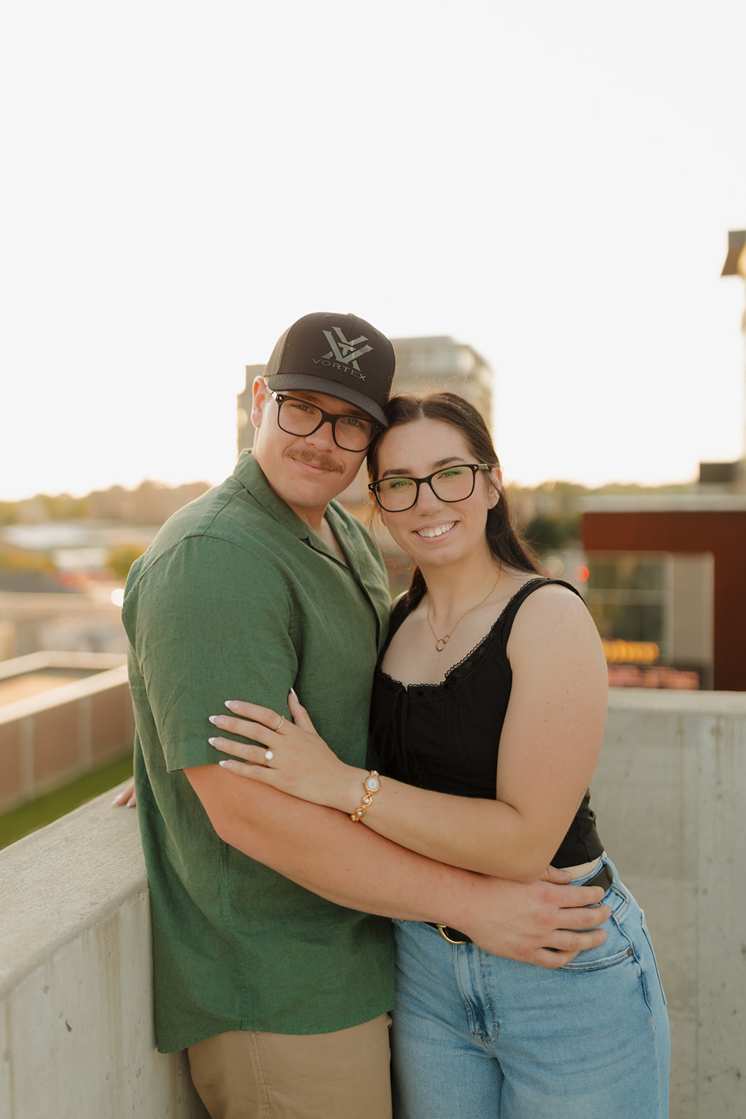 Modern rooftop engagement session with a couple holding each other and smiling in the glow of sunset.