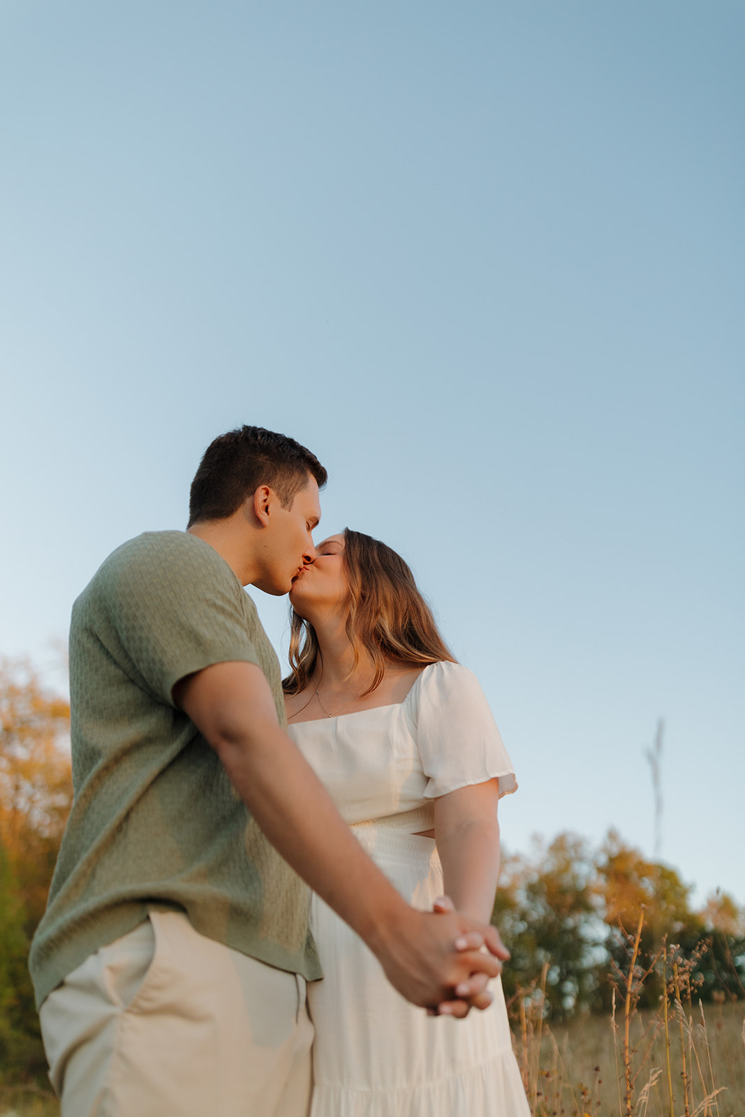 Sweet and simple moment as a couple shares a kiss beneath the open sky during their engagement session.