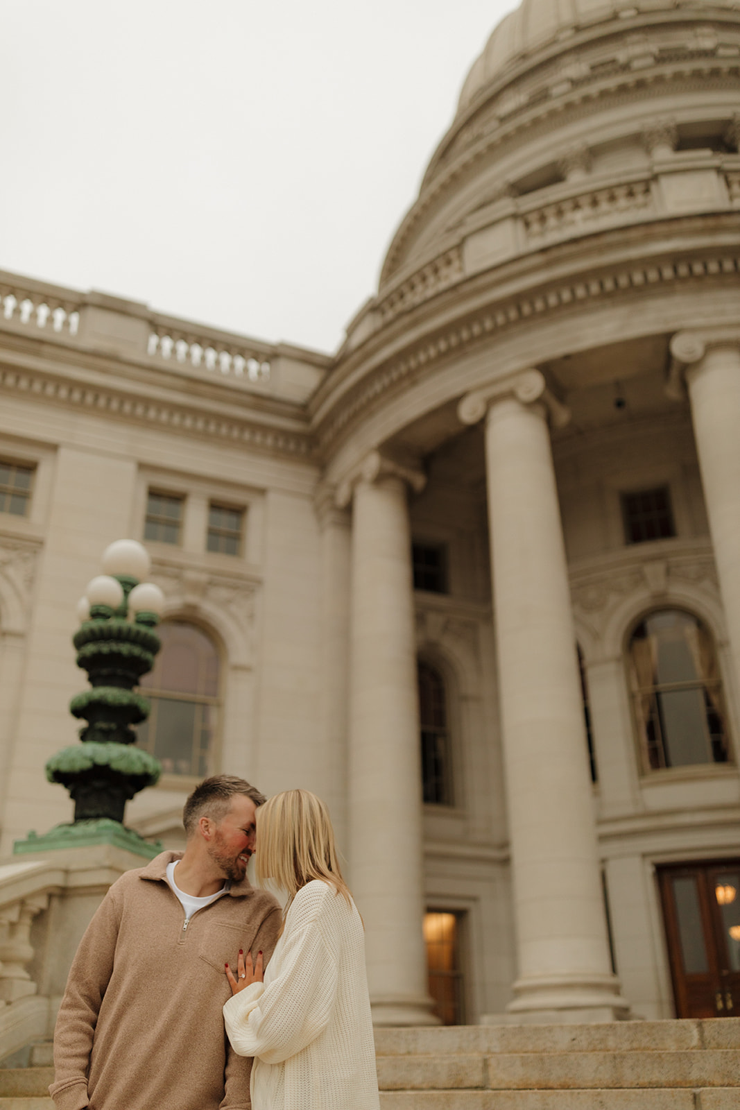 Engagement session moment with a couple sharing a quiet kiss outside the Wisconsin Capitol.