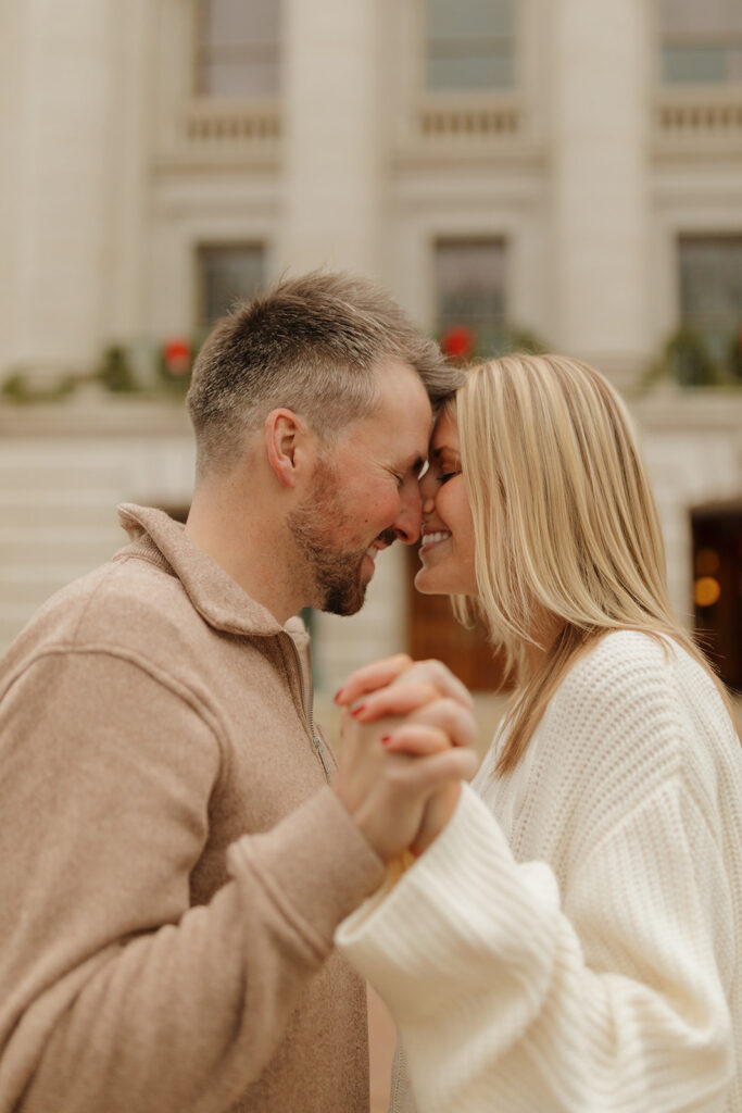 Sweet close-up of a couple holding hands and leaning in together on Capitol Square.

