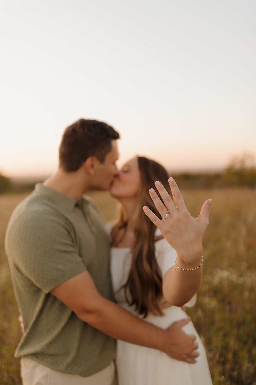 Outdoor engagement photos featuring a couple kissing at golden hour, her hand raised to show off the ring.