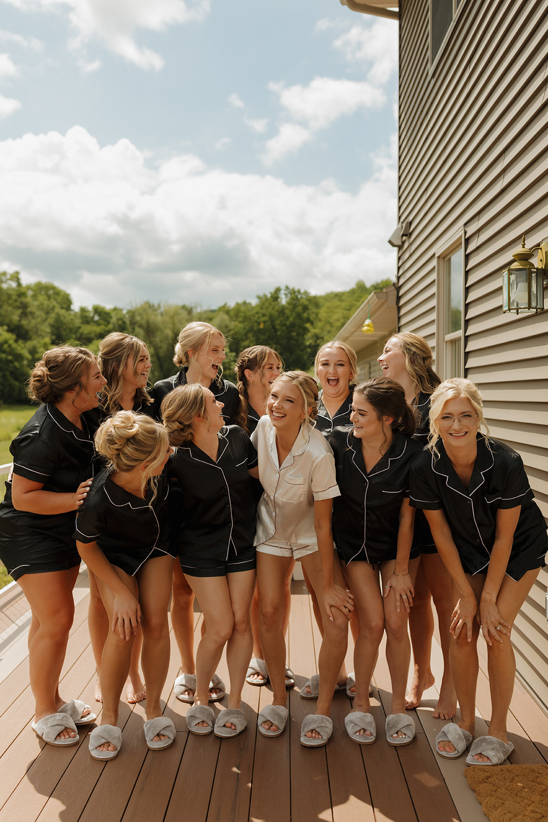 Bride and bridesmaids wearing matching pajamas and laughing together while getting ready for Wisconsin outdoor wedding
