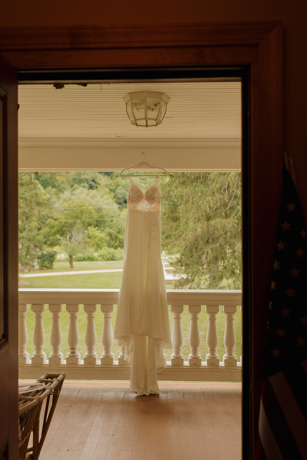 Lace wedding gown hanging from patio before outdoor wedding begins