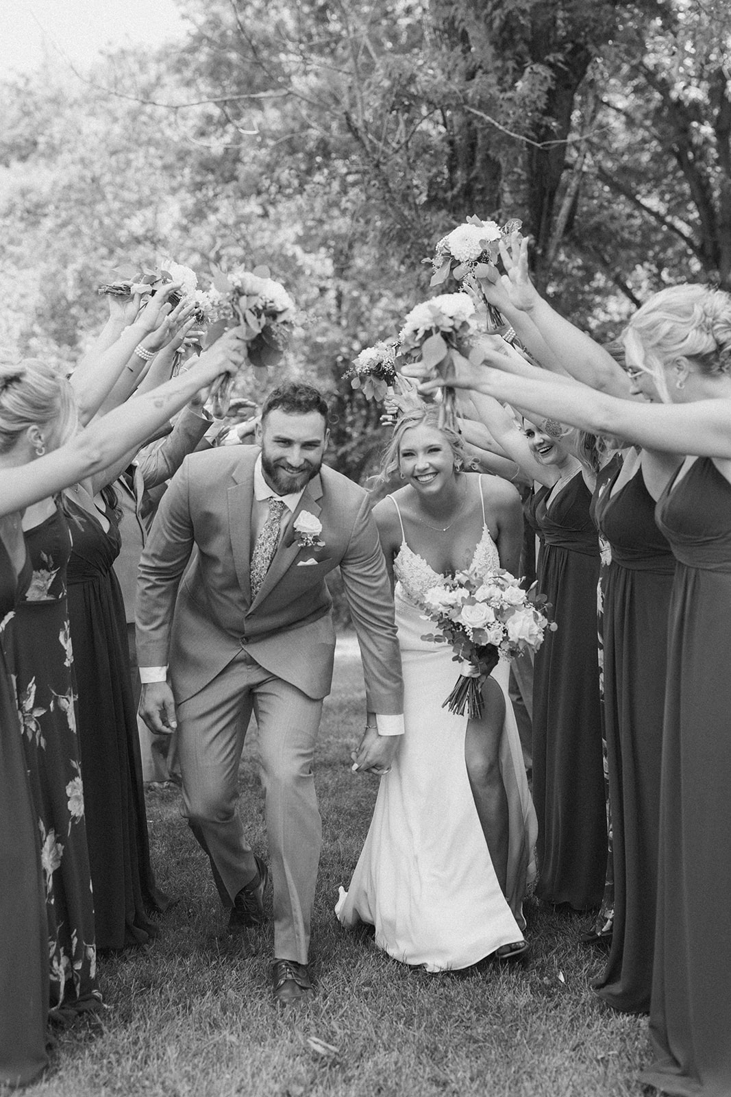 Bride and groom walking through tunnel of wedding party hands celebrating recent marriage, more fun outdoor wedding ideas coming to life