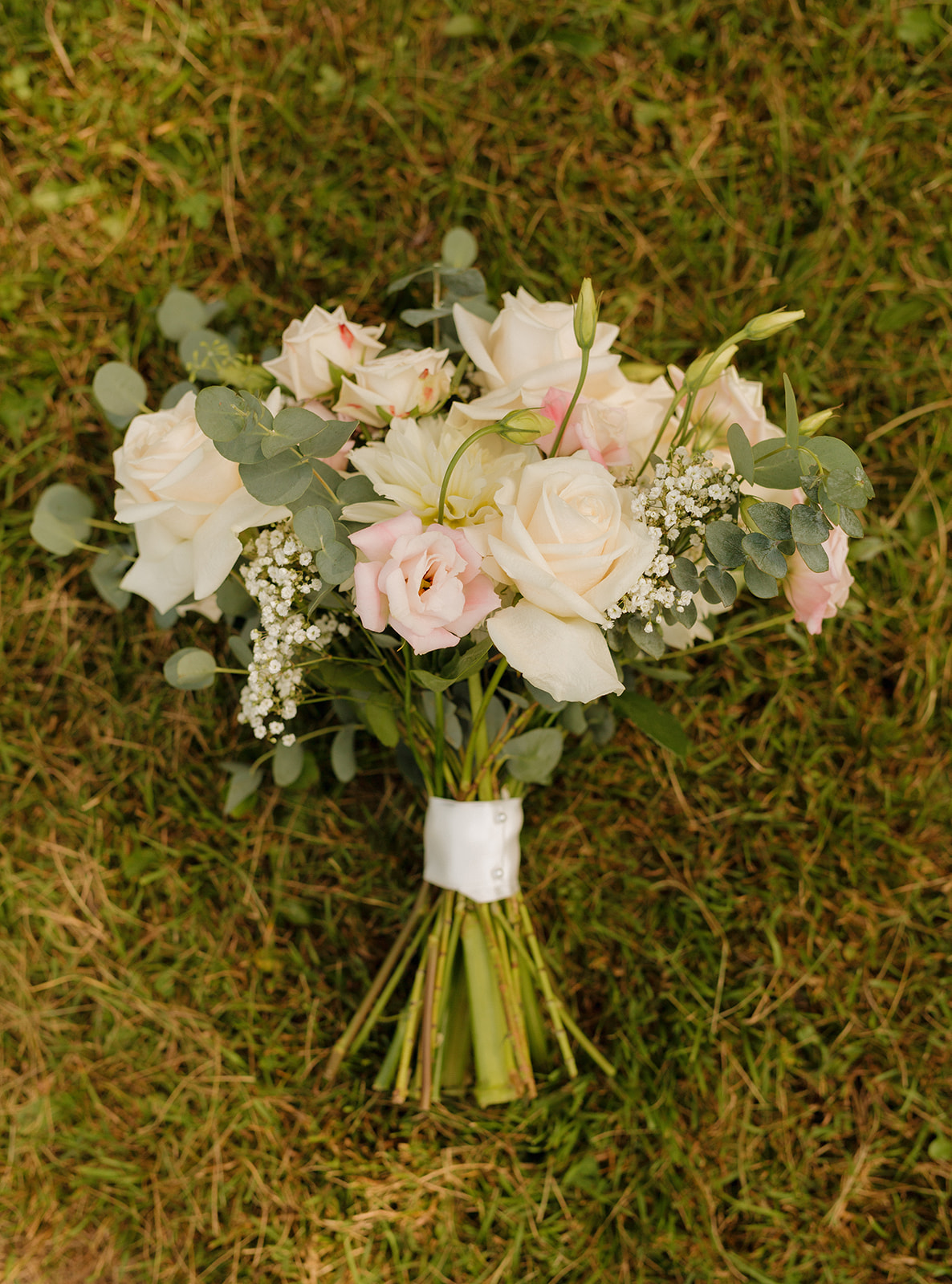 White and pink floral bouquet sitting in grass capturing elegant style and various floral types