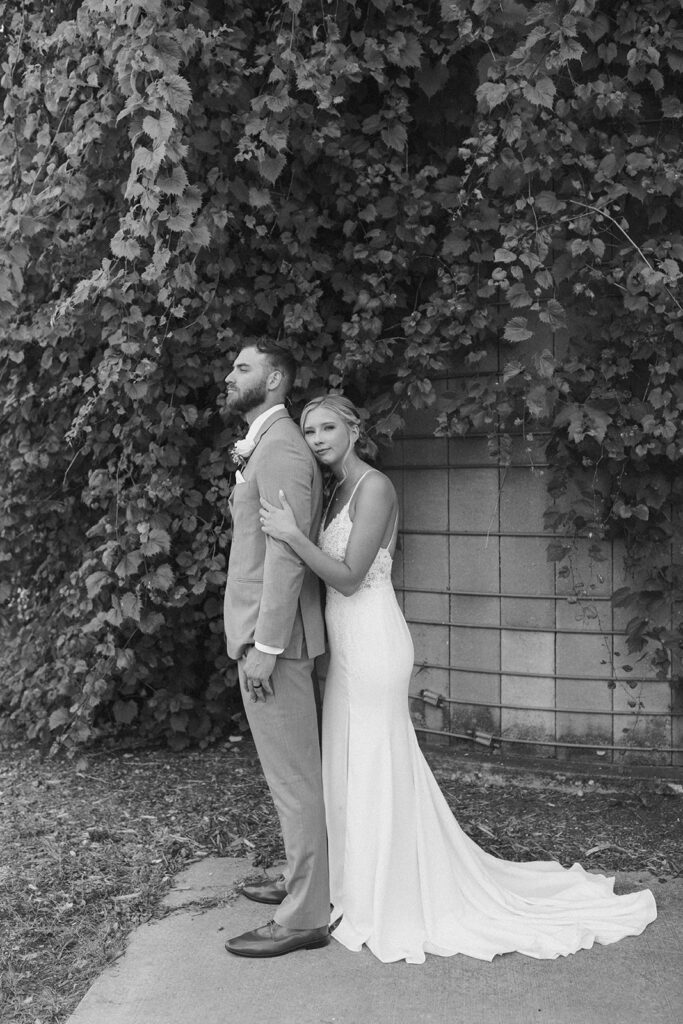 Bride resting her head on groom's back while hugging him from behind during outdoor bride and groom photos 