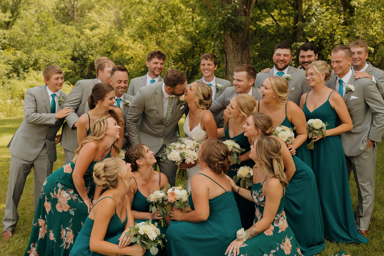 Wedding couple kissing while wedding party looks on celebrating and cheering in excitement