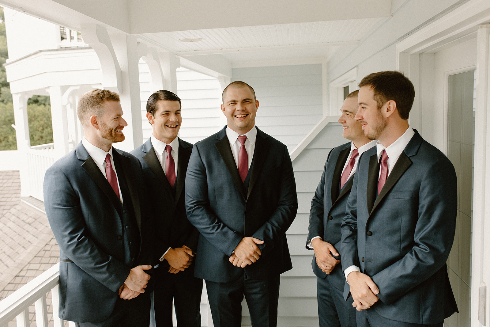 Groom laughing with his groomsmen on the balcony before the ceremony begins