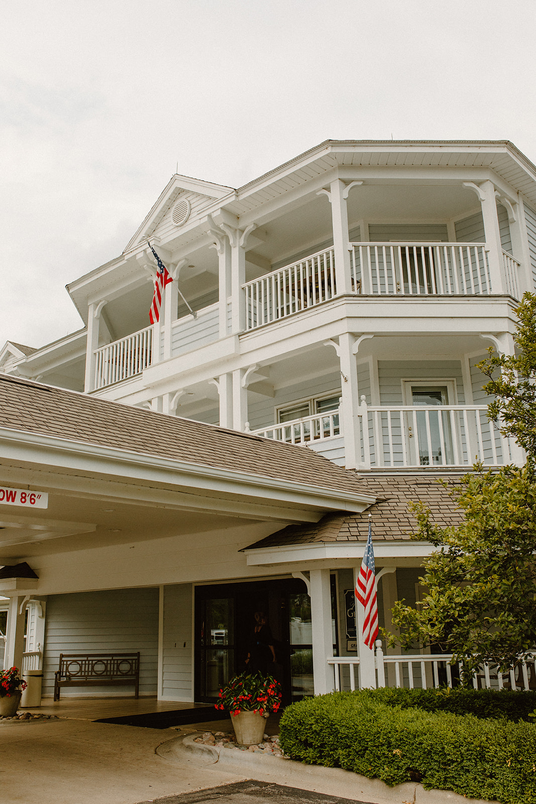 Exterior of a classic white inn with American flags and wraparound balconies in Lake Geneva