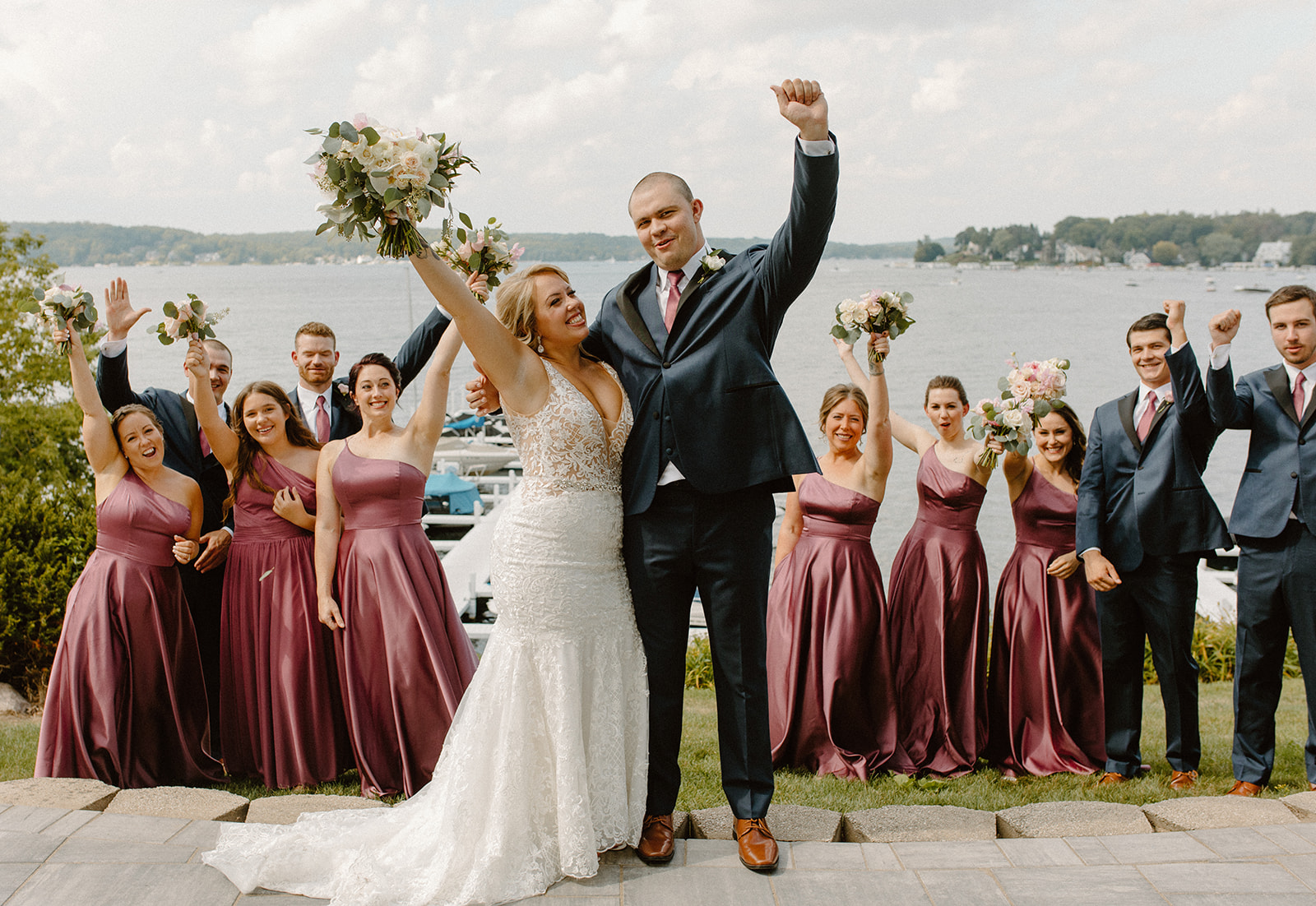 Wedding party cheering and celebrating with the bride and groom in front of Lake Geneva