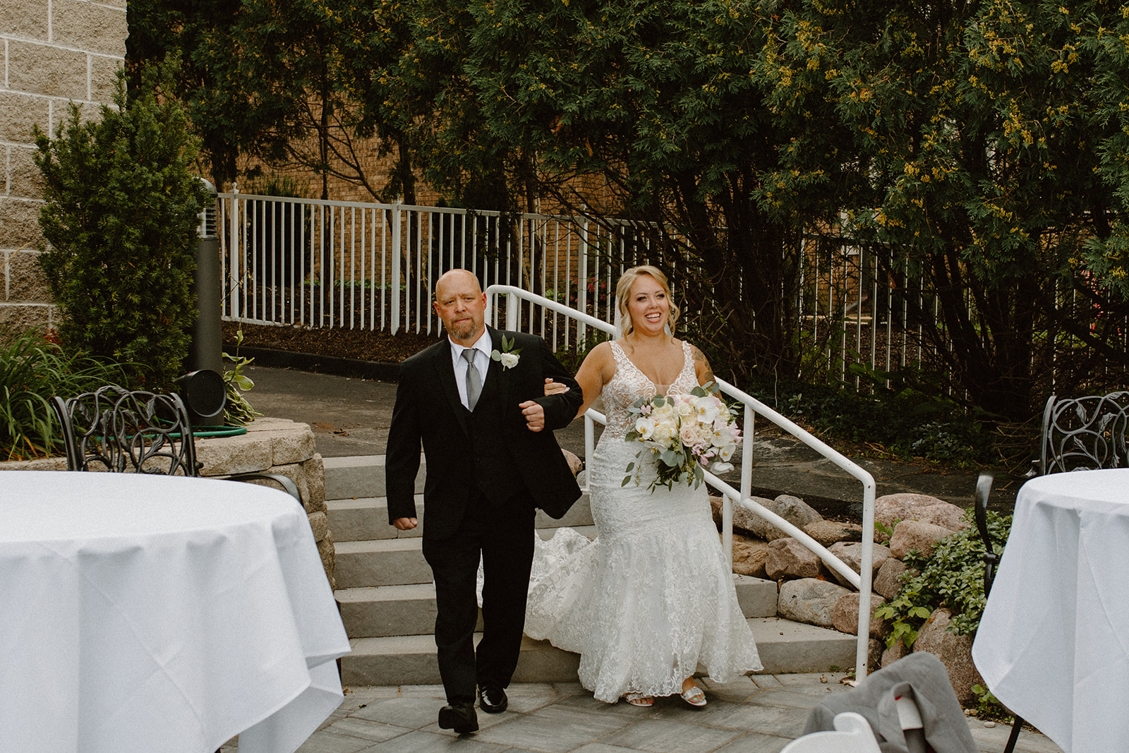 Bride walking down the aisle arm-in-arm with her father, smiling with anticipation