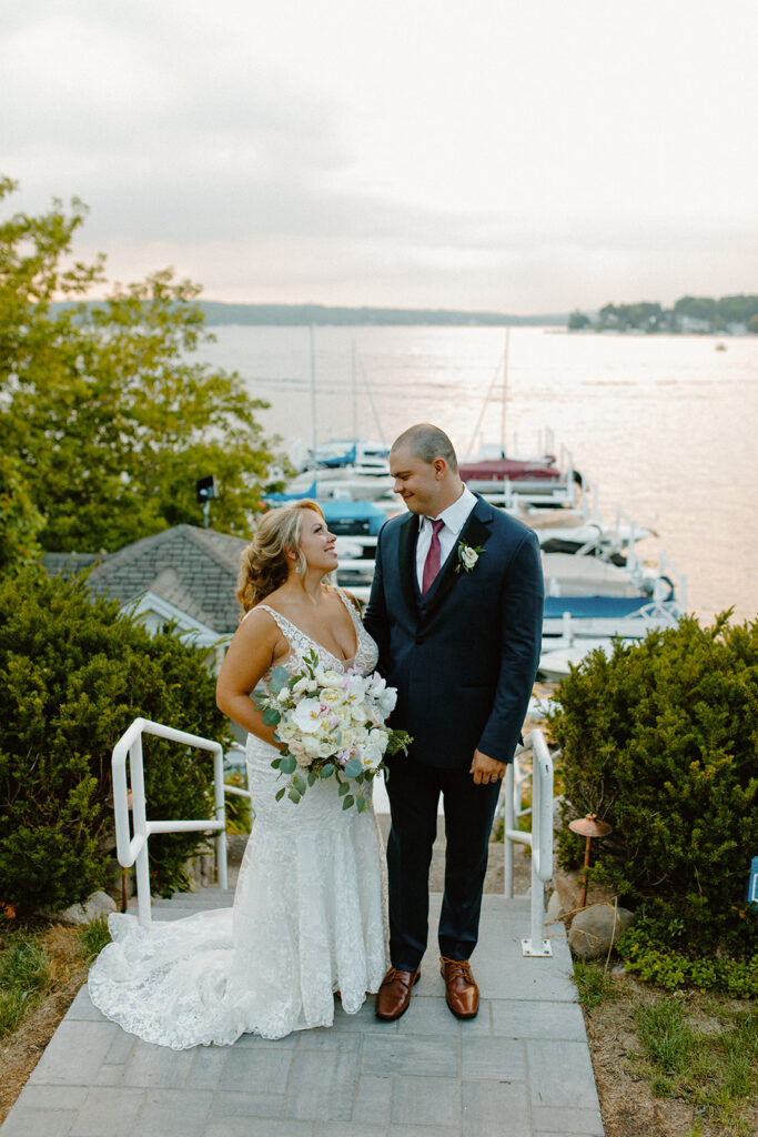 Newlyweds standing on lakeside steps, soaking in the golden hour glow and each other

