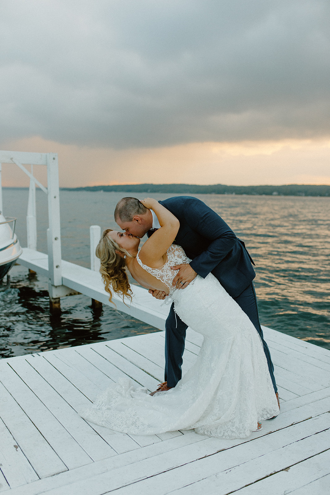 Groom dipping bride on the dock for a romantic kiss at sunset over Lake Geneva
