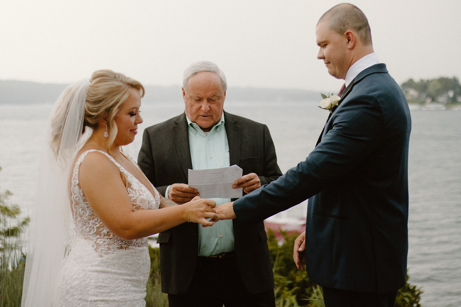 Bride and groom holding hands during their waterfront wedding vows