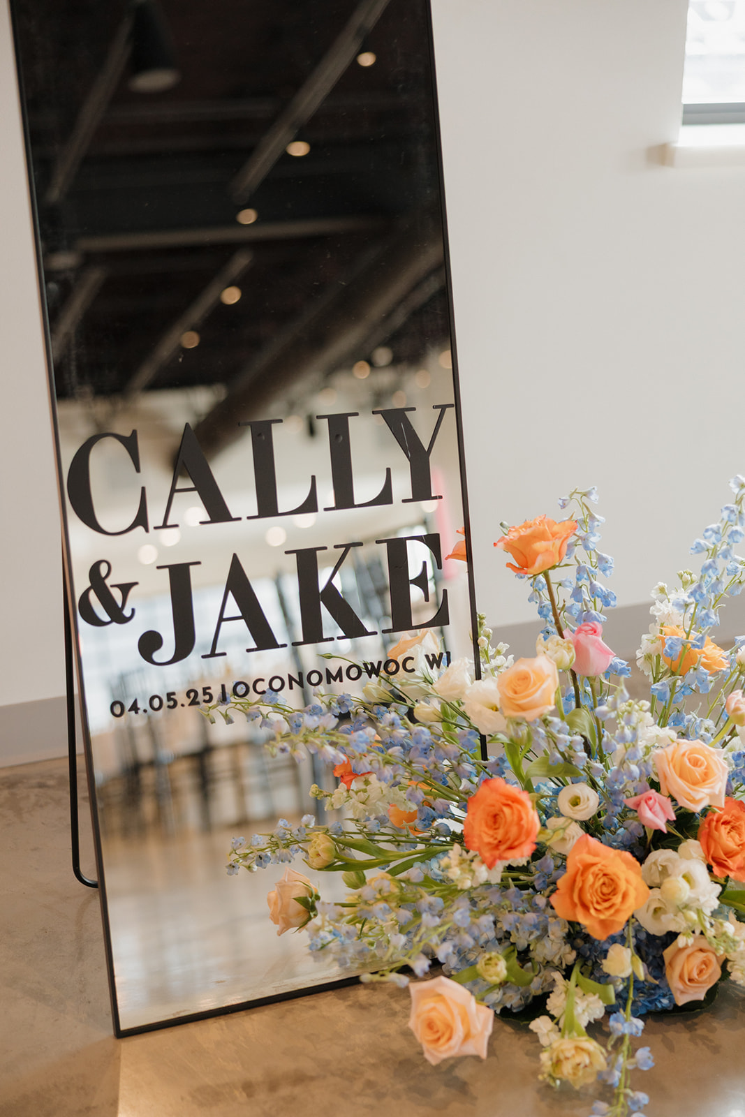 Elegant welcome sign with the couple’s names and wedding date, styled with lush spring florals.

