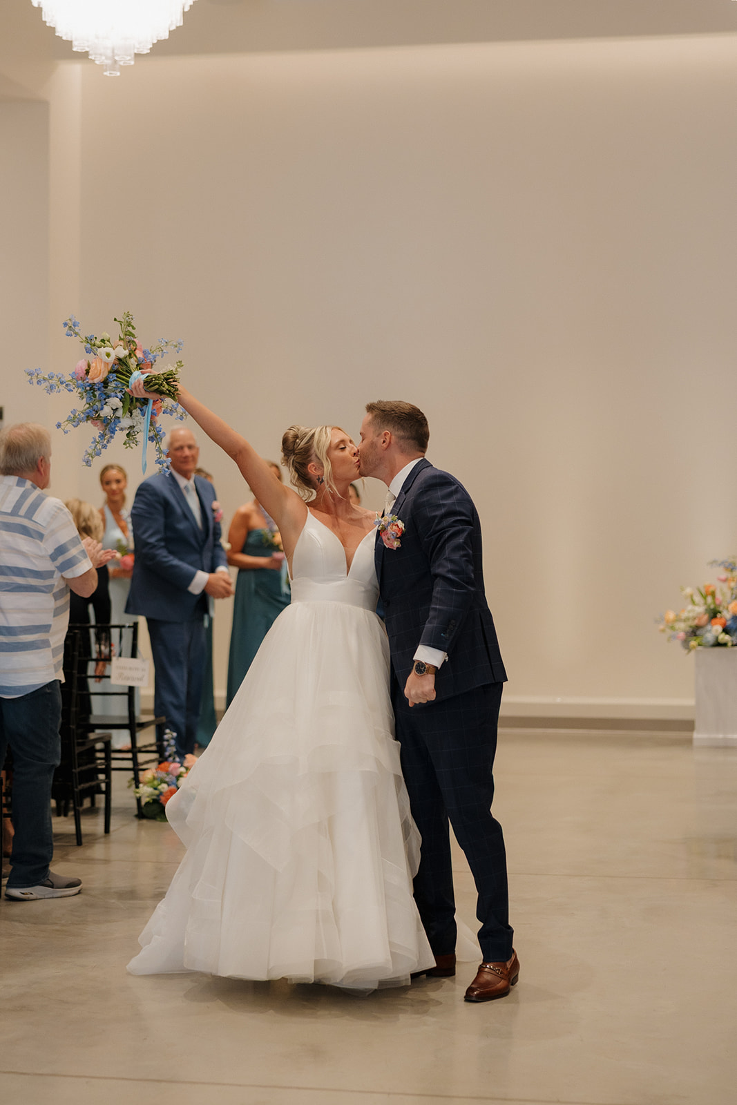 Just married and totally giddy—bride cheers with bouquet while sharing a kiss with her groom.

