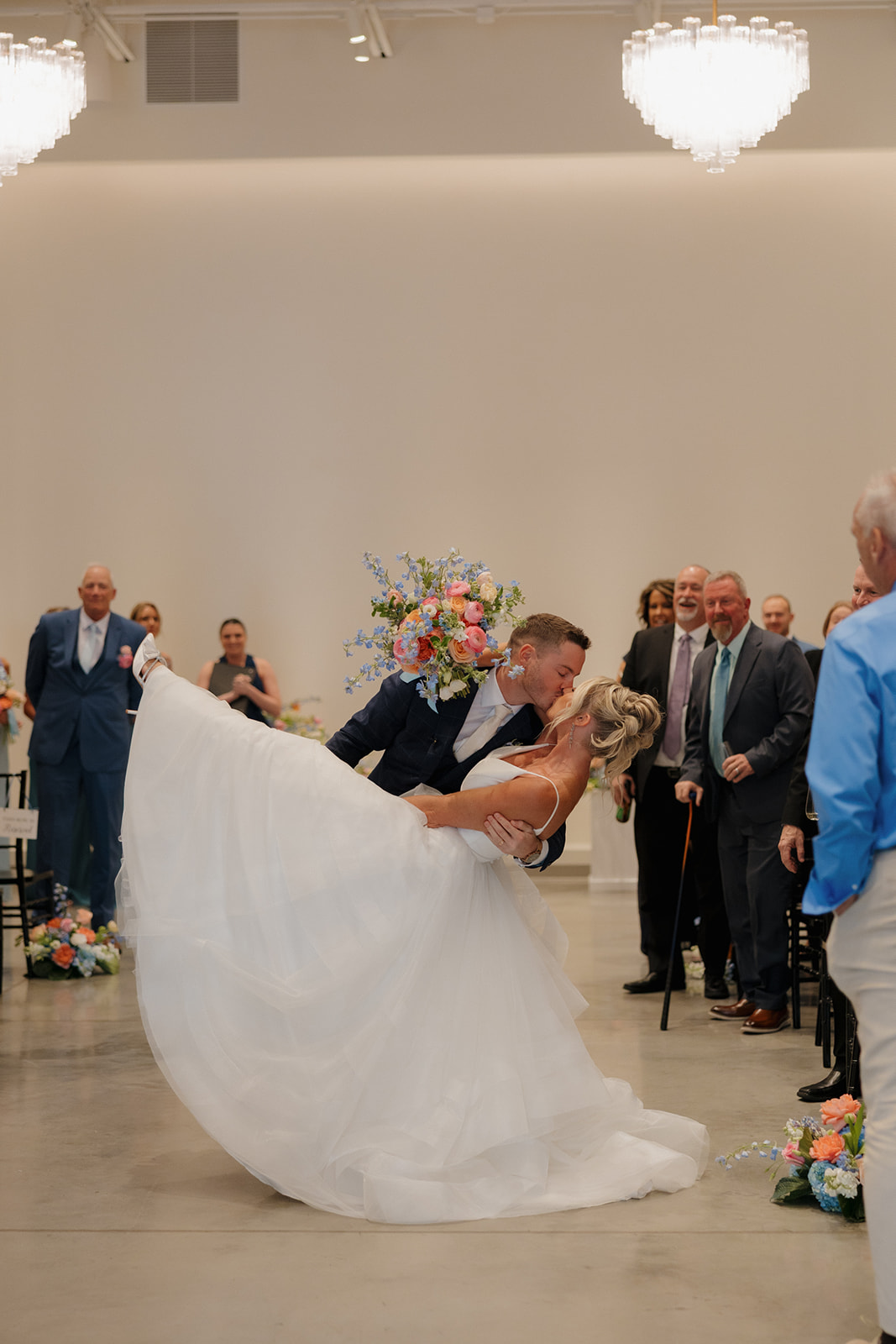 Groom dips bride for a dramatic kiss down the aisle as guests cheer during a joyful Madison Wisconsin wedding ceremony.