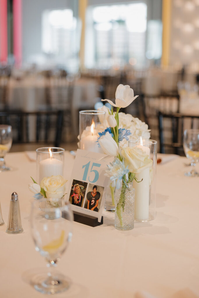 Modern wedding table centerpiece with tulips, candles, and a personalized table number featuring childhood photos.