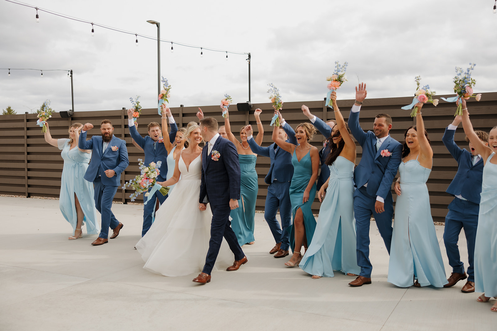 Bride and groom lead their wedding party in a joyful cheer outside their Madison Wisconsin wedding venue.