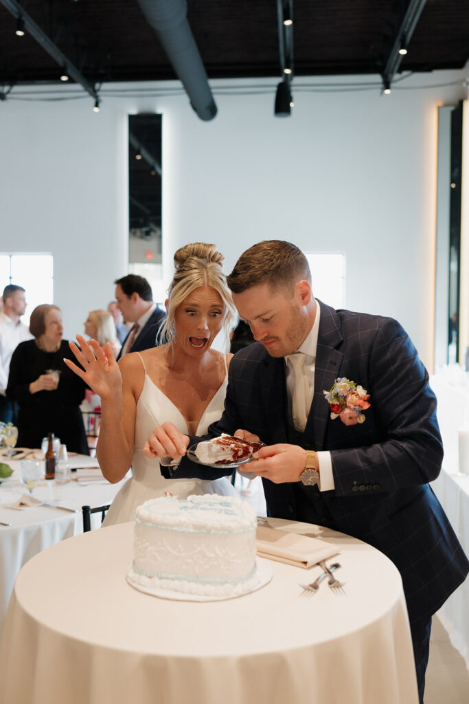 Bride gasps with excitement as the groom cuts a slice of their vintage heart-shaped cake. 